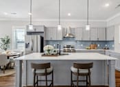 Thumbnail 2 of 38 - A modern kitchen with a large island and bar stools.
