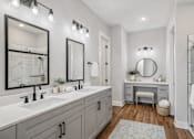 Thumbnail 6 of 38 - A bathroom with two sinks and a round mirror.