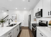 Thumbnail 42 of 56 - A modern kitchen with white cabinets and black appliances.