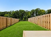 Thumbnail 55 of 56 - A long, narrow grassy area is flanked by a wooden fence on both sides.
