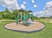 Thumbnail 17 of 20 - A playground with a green slide and a wooden structure.
