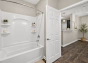 Thumbnail 7 of 20 - A bathroom with a white bathtub and a white door.