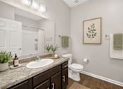 Thumbnail 8 of 20 - A bathroom with a white toilet, a sink, and a mirror.