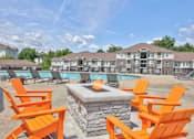 Thumbnail 15 of 20 - A fire pit sits in front of orange chairs in a pool area.