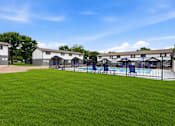 Thumbnail 16 of 23 - A grassy area with a pool and a building in the background.