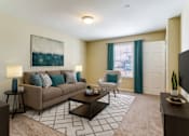 Thumbnail 21 of 21 - A living room with a beige couch, a painting on the wall, and a patterned rug.