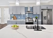Thumbnail 17 of 33 - A modern kitchen with a marble countertop and stainless steel appliances.