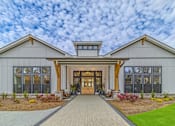 Thumbnail 2 of 41 - A modern house with a large front porch and a wooden walkway leading to the entrance.