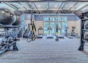Thumbnail 15 of 41 - A gym with a variety of equipment including weights and exercise machines.