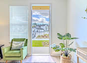 Thumbnail 32 of 41 - A room with a green chair and a potted plant.