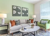 Thumbnail 26 of 41 - A living room with a grey couch, a green armchair, a coffee table, and two lamps.