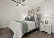 Thumbnail 8 of 23 - A bedroom with a bed, nightstand, and a ceiling fan.