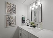 Thumbnail 10 of 23 - A bathroom with a white sink and a mirror with lights above it.