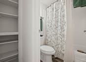 Thumbnail 11 of 23 - A white toilet in a bathroom with a shower curtain.