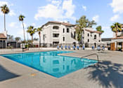 Thumbnail 14 of 23 - A swimming pool in front of a building with palm trees.