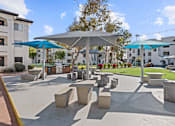 Thumbnail 16 of 23 - A sunny day at a park with concrete benches and umbrellas.