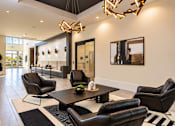 Thumbnail 24 of 30 - A modern living room with black leather chairs and a wooden coffee table.