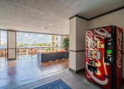 Thumbnail 9 of 35 - A Coca-Cola vending machine is in a room with a view of a balcony and buildings outside.