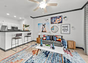 Thumbnail 1 of 29 - A modern kitchen with a bar area and a living room area with a couch and a rug.
