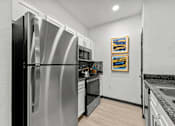Thumbnail 17 of 29 - A kitchen with a stainless steel refrigerator and a painting on the wall.