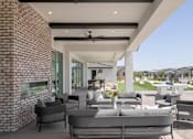 Thumbnail 19 of 21 - A modern outdoor seating area with a brick wall and a ceiling fan.