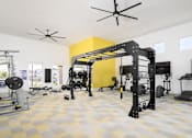 Thumbnail 17 of 21 - A home gym with a yellow wall and a ceiling fan.