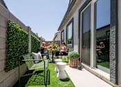 Thumbnail 12 of 21 - A small patio with a table and chairs and a green wall.