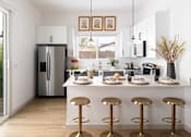 Thumbnail 1 of 21 - A kitchen with a white counter and gold stools.