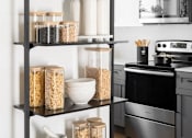 Thumbnail 2 of 21 - A black shelf with various food items and containers on it.