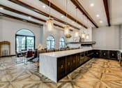 Thumbnail 23 of 33 - A large, well-lit kitchen with a marble countertop and a dining area with chairs and a table.