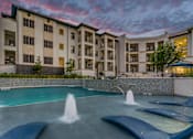 Thumbnail 29 of 33 - A large building with a pool in front of it.