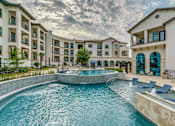 Thumbnail 25 of 33 - A large swimming pool in front of apartment buildings.
