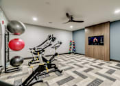 Thumbnail 16 of 33 - A home gym with a variety of exercise equipment and a television.
