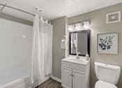 Thumbnail 6 of 16 - A white bathroom with a toilet, sink, and shower.