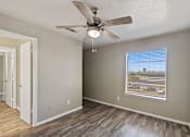 Thumbnail 9 of 16 - A room with a ceiling fan and a window overlooking a parking lot.