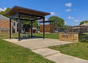 Thumbnail 14 of 16 - A pavilion with a picnic table is situated in a grassy area.