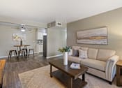 Thumbnail 1 of 16 - A living room with a couch, coffee table, and a painting on the wall.
