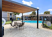 Thumbnail 12 of 16 - A patio with a table and chairs and a pool.