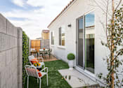 Thumbnail 10 of 19 - A patio with a table and chairs is surrounded by a wall and a tree.