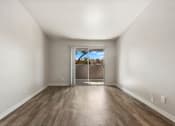 Thumbnail 8 of 20 - an empty living room with wood flooring and a door to a balcony