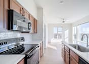 Thumbnail 6 of 28 - A modern kitchen with a stove top oven and microwave.