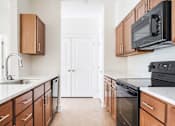 Thumbnail 5 of 28 - A kitchen with black appliances and wooden cabinets.