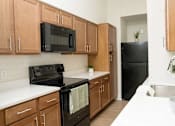 Thumbnail 9 of 28 - A kitchen with wooden cabinets and black appliances.