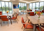 Thumbnail 19 of 28 - A room with tables and chairs and a TV on the wall.