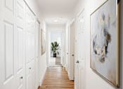 Thumbnail 28 of 33 - a hallway with white closets and paintings and a potted plant