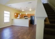 Thumbnail 2 of 16 - A room with wooden floors and a staircase.