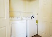 Thumbnail 10 of 16 - A white washing machine and dryer in a small laundry room.