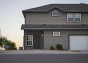 Thumbnail 12 of 16 - A house with a grey siding and a black door is shown.