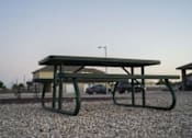 Thumbnail 16 of 16 - A green picnic table is on a gravel surface.