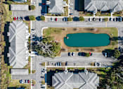 Thumbnail 4 of 39 - A bird's eye view of a parking lot with cars and a pond.